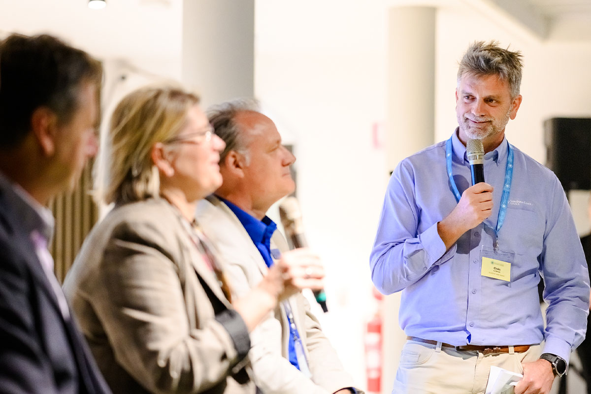 man talking to panel of speakers